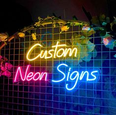 the neon sign says custom neon signs against a tiled wall with flowers and leaves on it