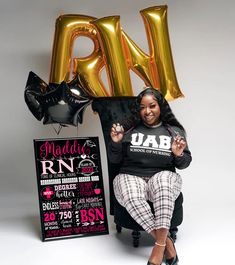 a woman sitting in a chair with some balloons on her head and a sign behind her