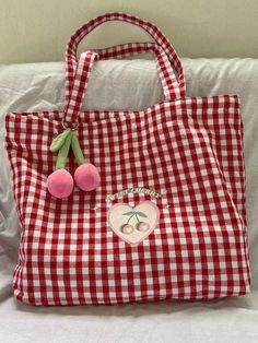 a red and white gingham bag with two pom - poms on it