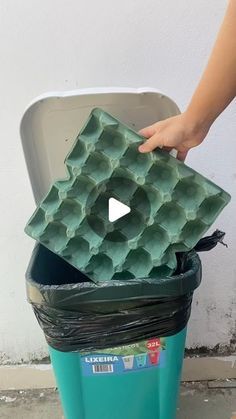 a person is placing an egg tray into a trash can