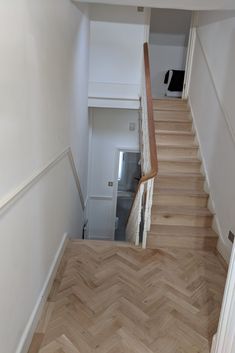 an empty hallway with wooden stairs and white walls