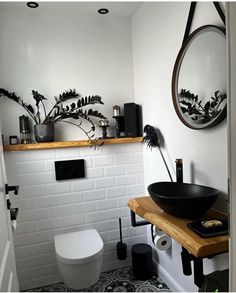 a black and white bathroom with plants on the wall above the toilet, sink and mirror