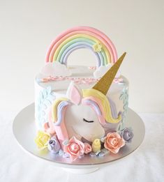 there is a cake decorated with a unicorn and flowers on the top, as well as a rainbow in the middle