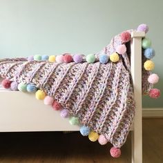 a crocheted blanket with pom - poms on it