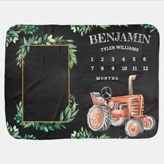 a black blanket with an orange tractor and green leaves on it, in front of a white background