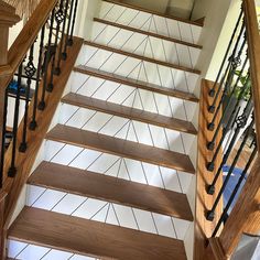 a stair case with wooden handrails and white tile on the floor below it