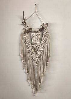 a macrame wall hanging on a white wall