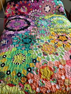 a multicolored quilt on top of a bed