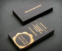 two black and gold business cards sitting on top of each other