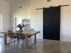 a dining room table and chairs in front of a barn door with sliding glass doors