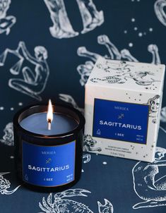 a candle sitting on top of a table next to a box of sagittarius