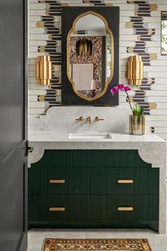 a bathroom with green cabinets and gold accents on the mirror above it is a rug that matches