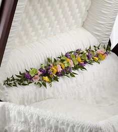 a bed with white ruffled sheets and flowers on it