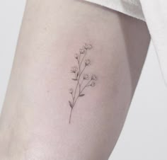 a small flower tattoo on the left side of the thigh, with tiny flowers growing out of it