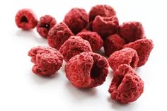 red raspberries are scattered on a white surface