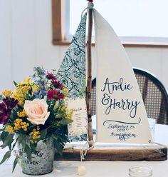 a sailboat is sitting on top of a table with flowers in the vases