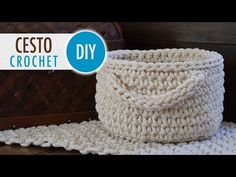 a crochet basket sitting on top of a wooden floor next to a blanket