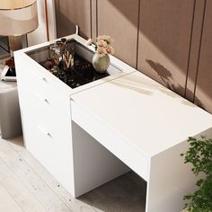 a white desk with drawers and plants in it