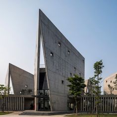 the building is made out of concrete and has triangular shaped windows on it's sides