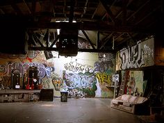 an empty room with graffiti on the walls and couches in front of it at night