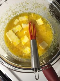 a bowl filled with yellow liquid next to a whisk on top of a stove