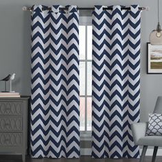 a gray and white curtain hanging on a wall next to a chair in front of a window