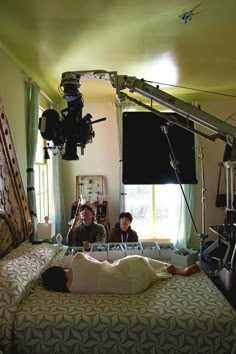 two people are laying on a bed in front of a camera set up for filming