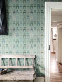 a wooden bench in front of a wallpapered hallway