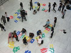 many people are standing around playing with letters on the floor