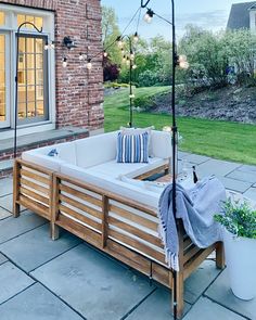 a wooden bench sitting on top of a patio next to a brick building and potted plants