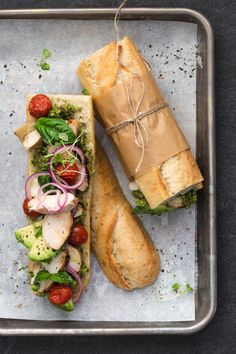 two sandwiches are sitting on a tray with some toppings next to eachother