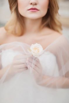 a woman wearing a veil and holding a flower