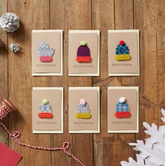 four christmas cards with knitted hats on them next to presents and pineconi