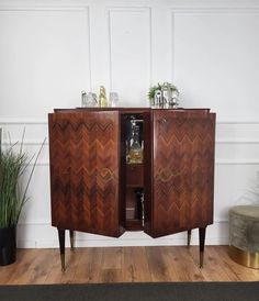 a wooden cabinet sitting on top of a hard wood floor next to a potted plant