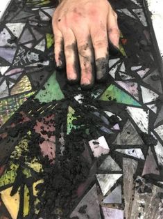 a person's hand on top of a piece of art that is covered in dirt