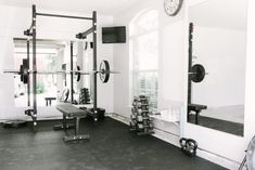 a home gym with black and white tiles on the floor, wall mounted weight racks