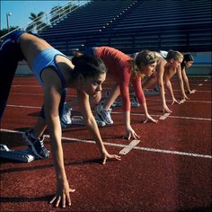 three women are lined up on the starting line to start a race in a stadium