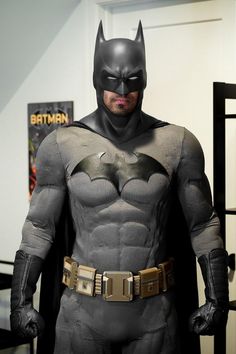 a man dressed as batman standing in front of a poster