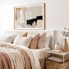 a bed with white sheets and pillows in a bedroom next to a painting on the wall