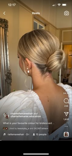 a woman with blonde hair in a white dress looking at her cell phone and wearing earrings