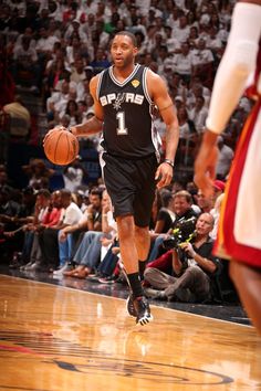 a basketball player dribbling the ball down the court while people watch from the stands