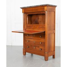 an old wooden desk with marble top and drawers on the bottom, in front of a white wall