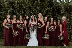 a group of women standing next to each other in front of some bushes and trees