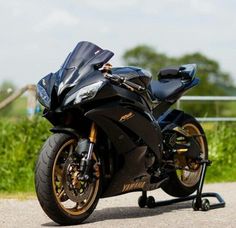 a black motorcycle parked on the side of a road next to a lush green field