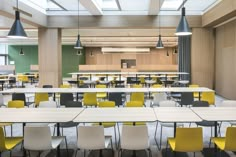 an empty classroom with tables and yellow chairs