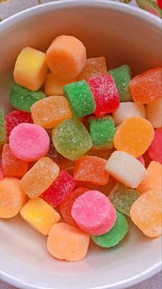 a white bowl filled with lots of gummy bears on top of a tablecloth