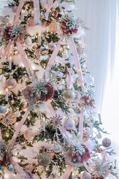 a decorated christmas tree with pink ribbons and ornaments