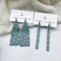 three pairs of earrings are shown on top of a white cloth background, one is green and the other is blue