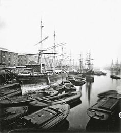 an old black and white photo of several ships in the water with buildings in the background