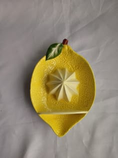 a yellow plate with an origami decoration on it's edge, sitting on a white sheet